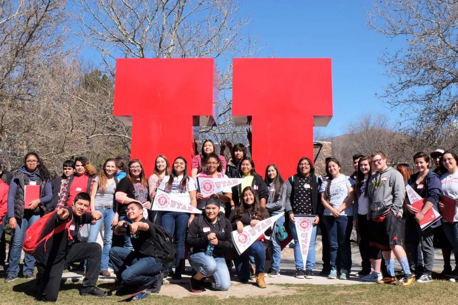 Students on campus pose in front of large red "U"